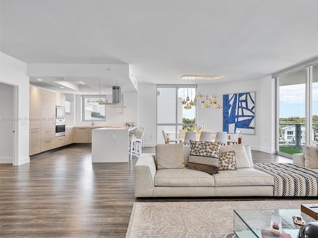 living room with a notable chandelier, baseboards, and dark wood-style flooring