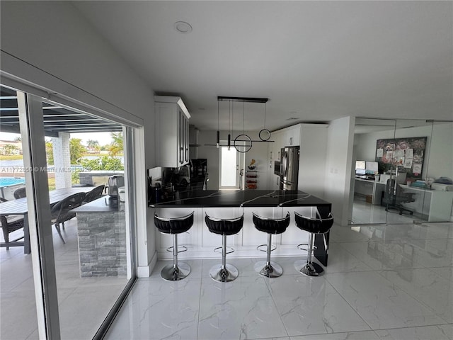 1531 SW 126th Pl, Miami, FL 33184 - kitchen featuring freestanding refrigerator, marble finish floor, a peninsula, dark countertops, and a breakfast bar area