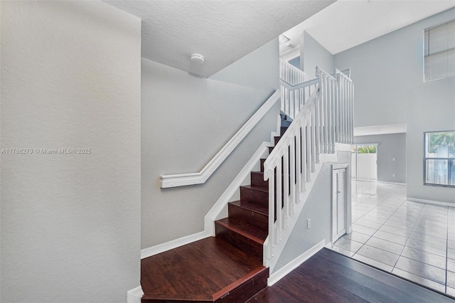 16122 SW 104th Ter, Miami, FL 33196 - staircase with baseboards, a towering ceiling, wood finished floors, and a textured ceiling