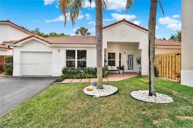 mediterranean / spanish-style home featuring stucco siding, an attached garage, a tiled roof, and a front lawn