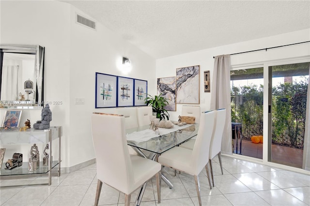 dining space featuring visible vents, tile patterned flooring, and a textured ceiling