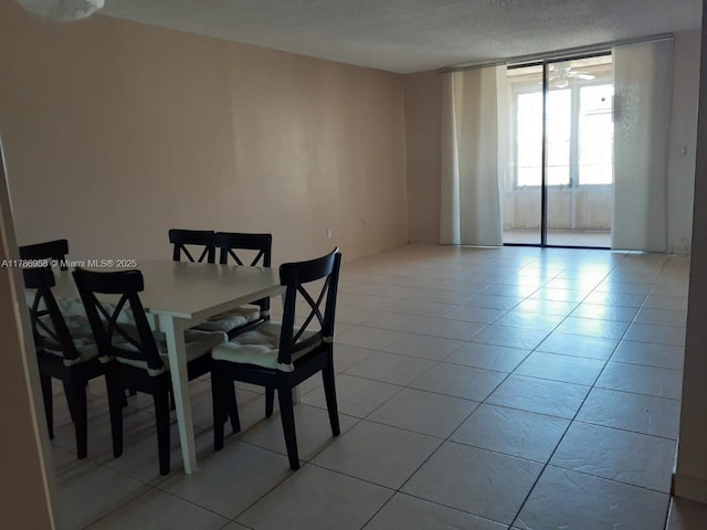 dining space with floor to ceiling windows, a textured ceiling, and light tile patterned floors