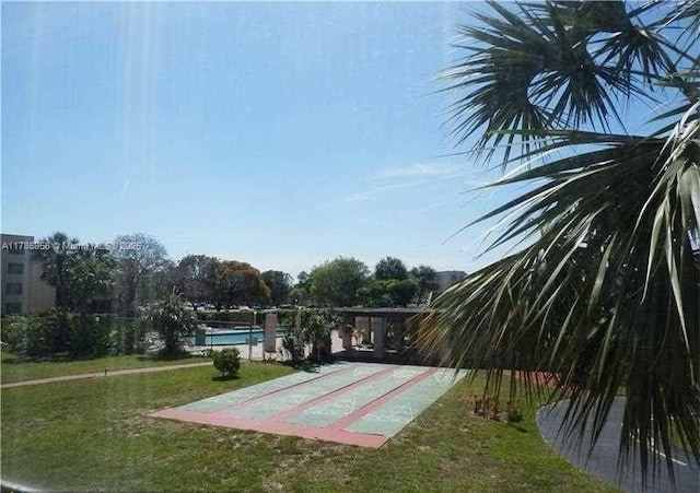 view of community featuring a lawn, shuffleboard, and a swimming pool