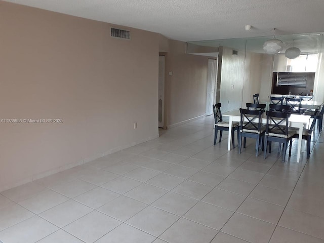 dining room with baseboards, visible vents, a textured ceiling, and light tile patterned floors