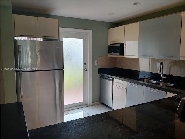 5950 Del Lago Cir Unit 112, Sunrise, FL 33313 - kitchen featuring appliances with stainless steel finishes, dark countertops, decorative backsplash, light tile patterned flooring, and white cabinetry