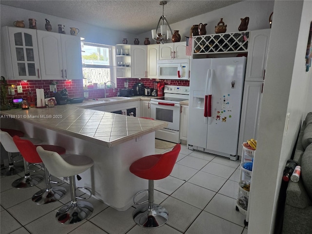 13061 SW 56th Ter, Miami, FL 33183 - kitchen featuring a textured ceiling, a breakfast bar area, a sink, white appliances, and a peninsula