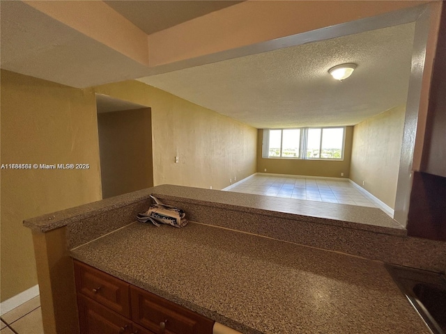 spare room with baseboards, a textured ceiling, and light tile patterned floors