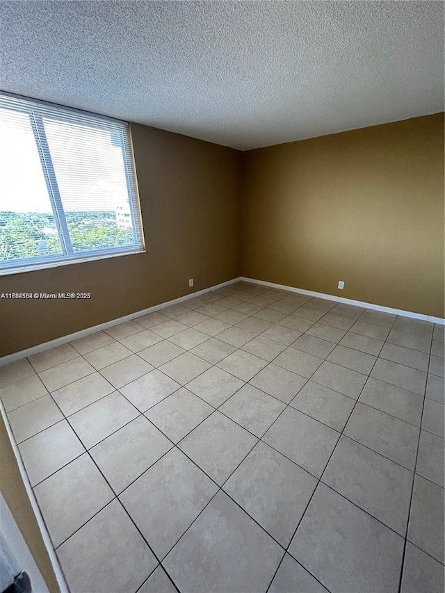 unfurnished room featuring a textured ceiling, baseboards, and light tile patterned floors