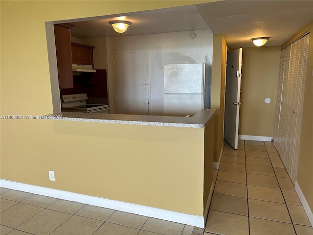 interior space with under cabinet range hood, light tile patterned floors, white appliances, baseboards, and a peninsula
