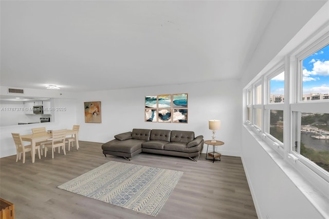 living room with wood finished floors, visible vents, and baseboards