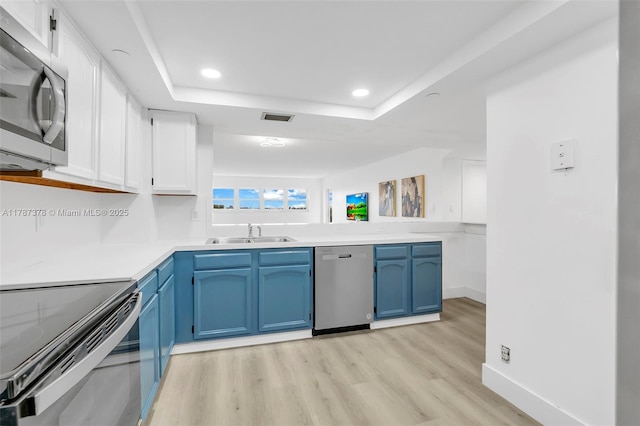 kitchen with stainless steel appliances, visible vents, blue cabinets, a sink, and light wood-type flooring