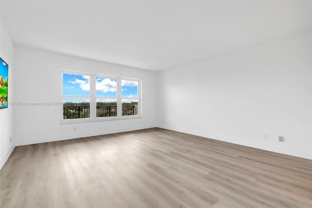 empty room with baseboards and wood finished floors