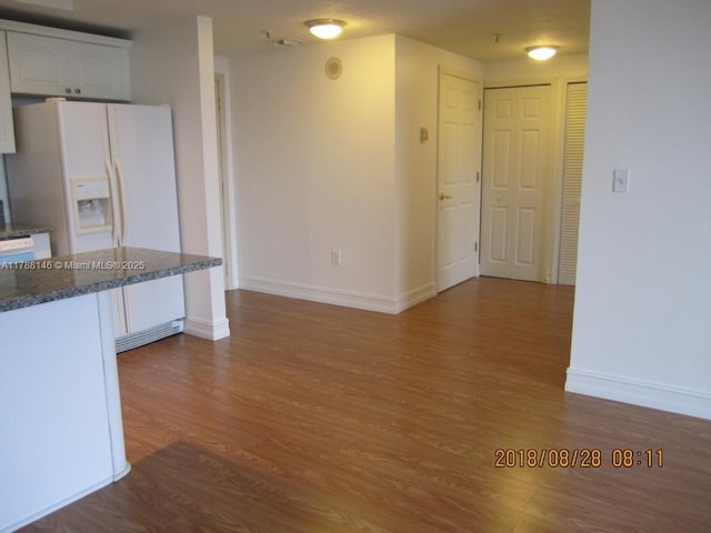 3500 Coral Way Unit 903, Miami, FL 33145 - kitchen featuring white fridge with ice dispenser, wood finished floors, baseboards, and white cabinetry