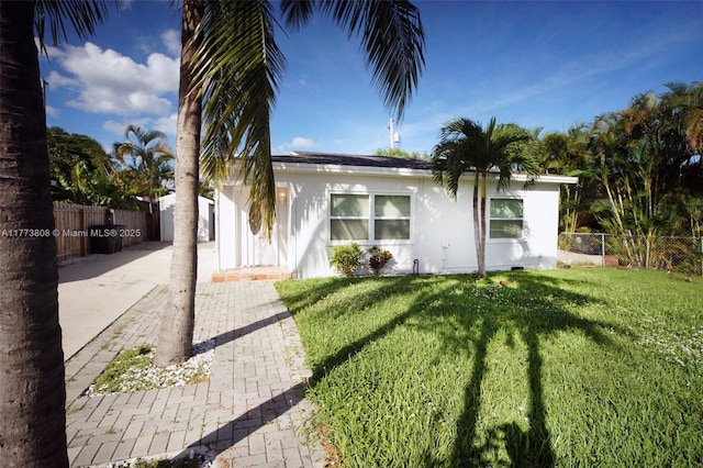 621 Hudson Rd, West Palm Beach, FL 33405 - view of front of home featuring fence, driveway, a front lawn, and stucco siding