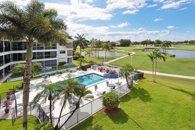 community pool with fence, golf course view, a water view, a patio area, and a lawn