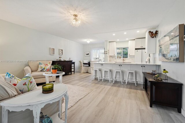 living room with recessed lighting, light wood finished floors, and a notable chandelier