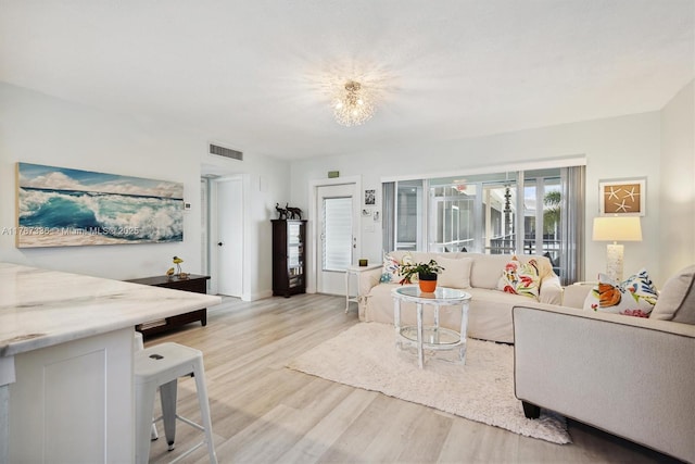 living area featuring a notable chandelier, visible vents, and light wood-style floors