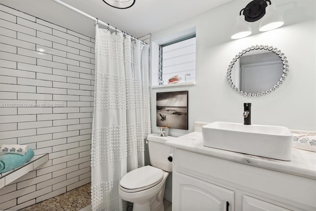 full bathroom with a tile shower, toilet, and vanity
