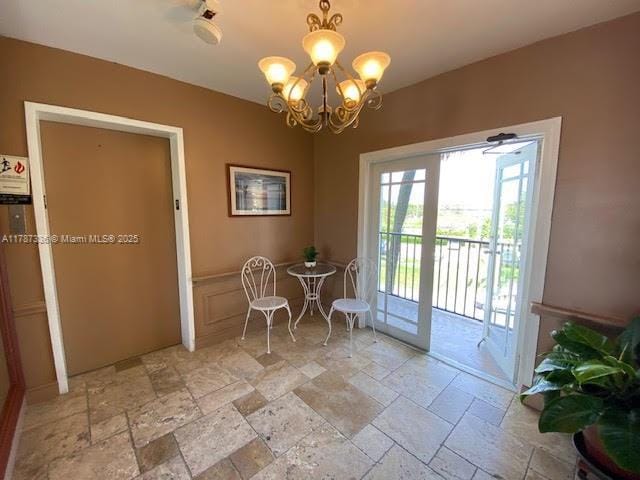 doorway to outside featuring stone tile flooring and an inviting chandelier
