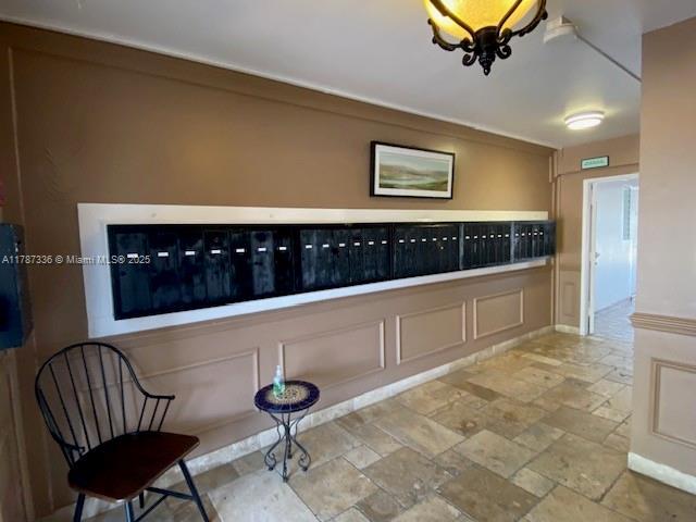 interior space featuring a decorative wall, stone tile floors, and mail area