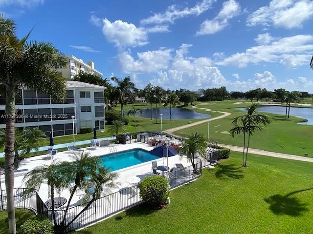 community pool with a yard, a patio, a water view, and fence