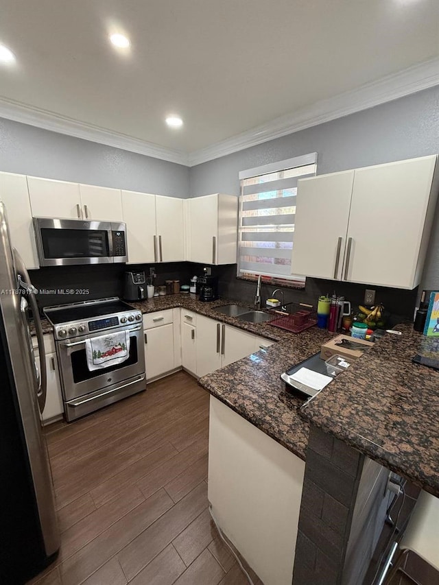 7353 NW 174th Ter Unit 107, Hialeah, FL 33015 - kitchen with appliances with stainless steel finishes, crown molding, white cabinetry, a peninsula, and dark wood-style floors