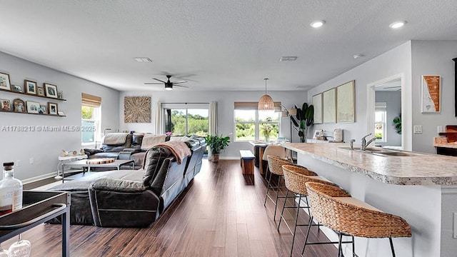 living room featuring a textured ceiling, a ceiling fan, baseboards, and dark wood-style floors