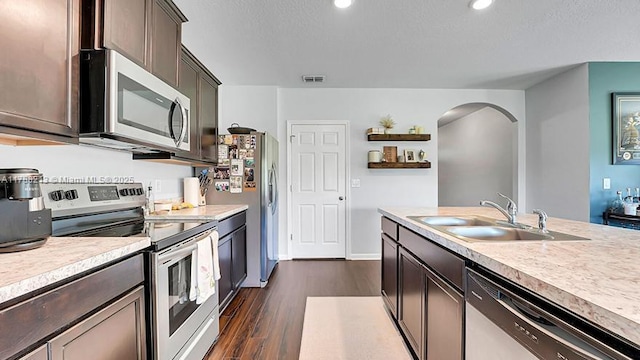kitchen featuring stainless steel appliances, light countertops, visible vents, a sink, and arched walkways