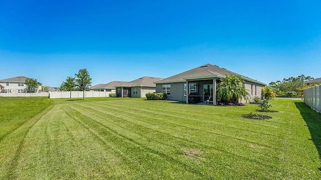 rear view of property featuring a lawn and fence