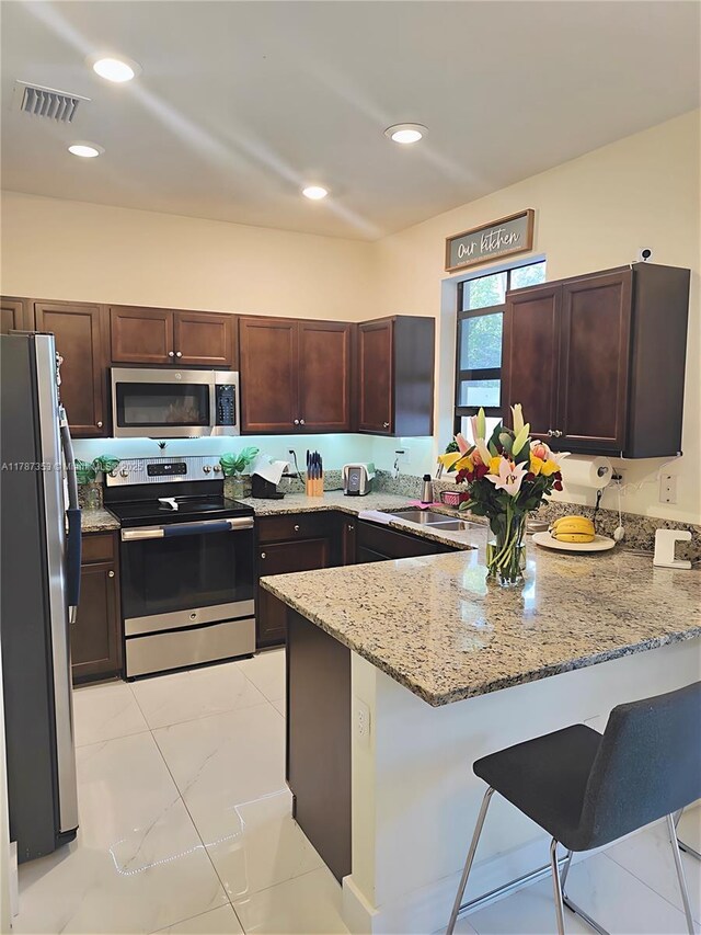 10315 W 32nd Ln, Hialeah, FL 33018 - kitchen with appliances with stainless steel finishes, a peninsula, light stone countertops, a kitchen breakfast bar, and light marble finish flooring