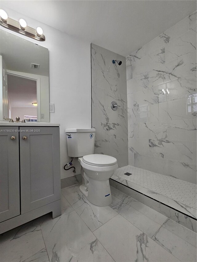 bathroom featuring marble finish floor, toilet, vanity, visible vents, and a marble finish shower
