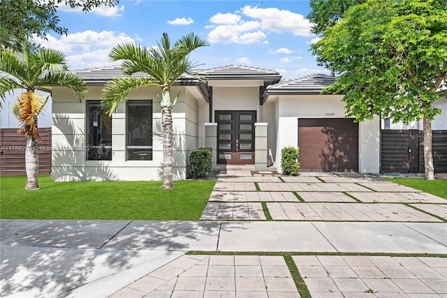 view of front of house featuring a front lawn, concrete driveway, an attached garage, a tile roof, and stucco siding
