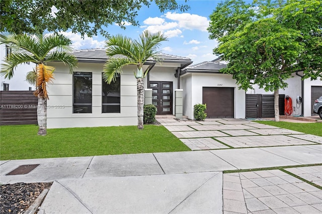 view of front facade featuring a front lawn, driveway, a tiled roof, an attached garage, and stucco siding
