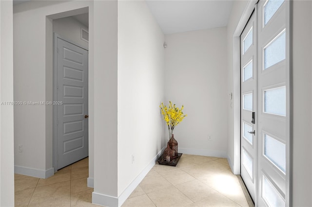 hallway with visible vents, tile patterned floors, and baseboards