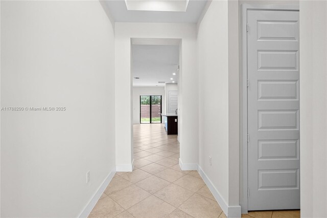 hall featuring baseboards and light tile patterned floors