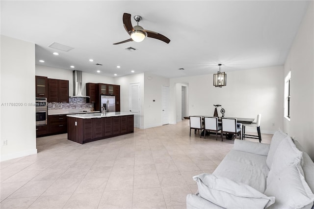 living area with ceiling fan with notable chandelier, baseboards, visible vents, and light tile patterned floors