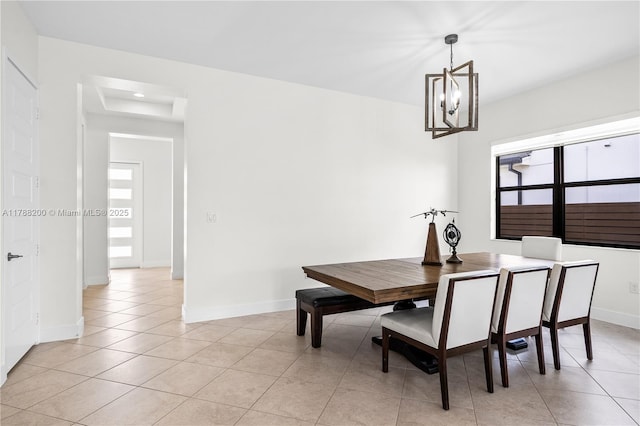 dining space featuring light tile patterned flooring, a raised ceiling, baseboards, and a notable chandelier
