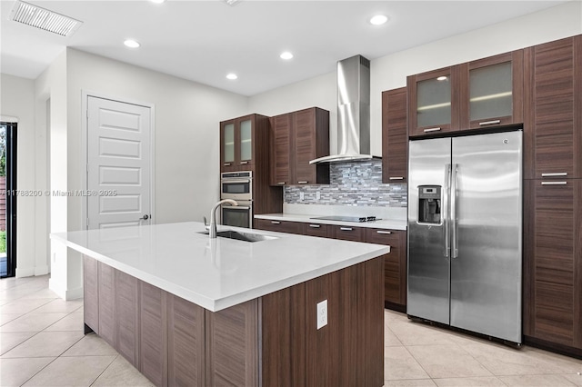 kitchen featuring stainless steel appliances, visible vents, a sink, light tile patterned flooring, and wall chimney exhaust hood