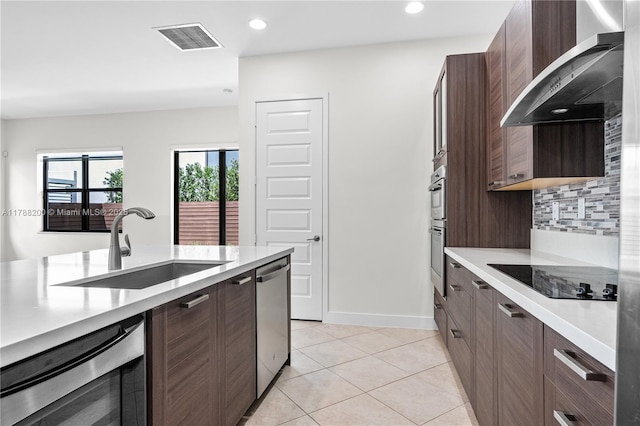 kitchen with black electric cooktop, visible vents, stainless steel dishwasher, a sink, and wall chimney exhaust hood
