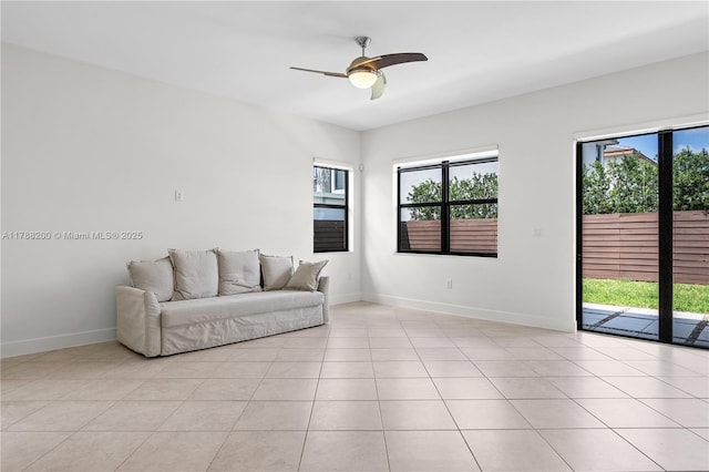 living area with ceiling fan, baseboards, a healthy amount of sunlight, and light tile patterned floors