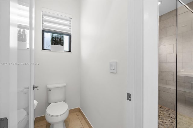 bathroom with a tile shower, tile patterned flooring, and toilet