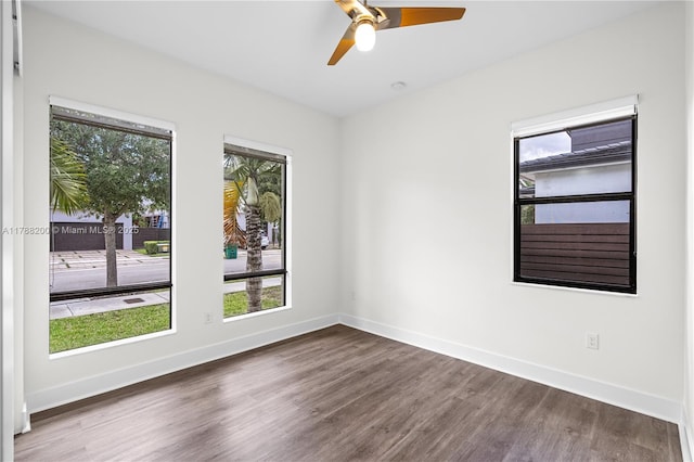 empty room with wood finished floors, a ceiling fan, and baseboards