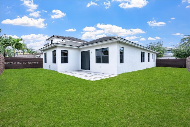 rear view of house with a patio area, a fenced backyard, a yard, and stucco siding