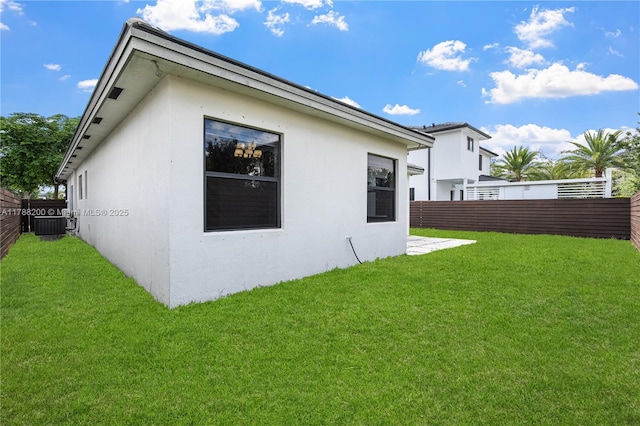 view of side of home featuring a lawn, stucco siding, and fence