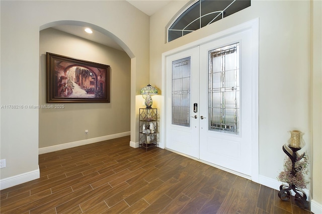 entrance foyer with arched walkways, baseboards, and french doors