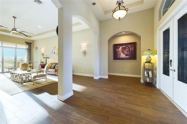 foyer with a raised ceiling, visible vents, a ceiling fan, and baseboards