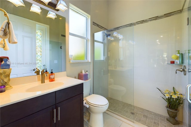 bathroom featuring a wealth of natural light, toilet, tiled shower, and vanity