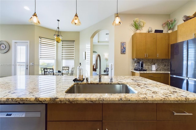 kitchen with arched walkways, a sink, tasteful backsplash, dishwasher, and hanging light fixtures