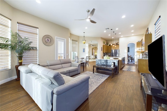 living room with dark wood-style floors, arched walkways, baseboards, recessed lighting, and ceiling fan