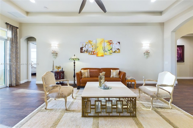 living room with baseboards, a ceiling fan, wood finished floors, and arched walkways